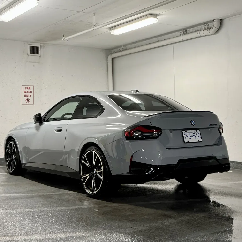 Grey BMW coupe in an underground parkade wash bay with a wet floor